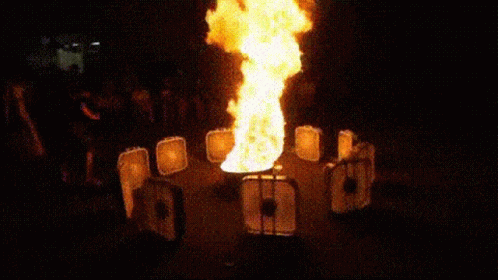 A Fire Is Coming Out Of A Container In A Dark Room . GIF
