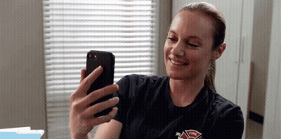 A Firefighter Is Taking A Selfie With Her Cell Phone . GIF
