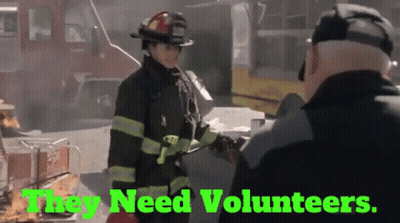 A Firefighter Talking To Another Firefighter With The Words " They Need Volunteers " Behind Her GIF