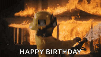 A Fireman Is Standing In Front Of A Burning House Holding A Hose And Saying Happy Birthday . GIF