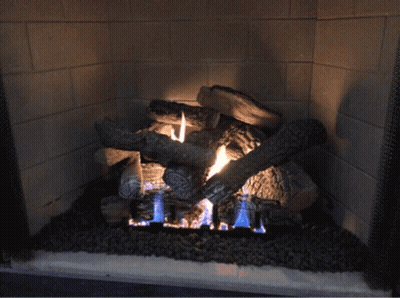A Fireplace Filled With Logs And A Blue Flame GIF