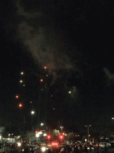 A Fireworks Display In A Parking Lot With A Crowd Watching GIF