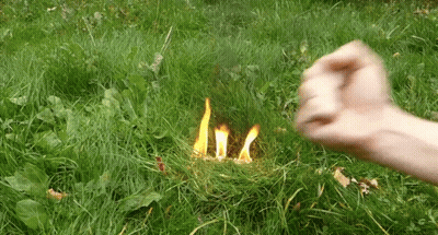 a fist is being thrown at a fire in the grass