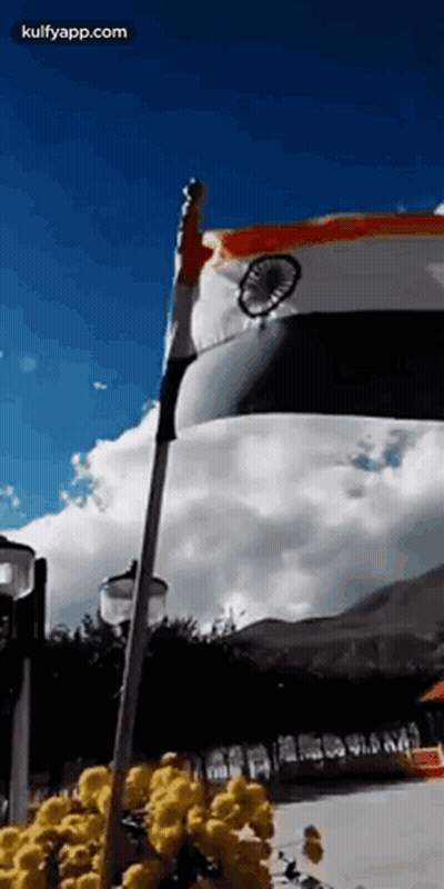 A Flag Is Waving In The Wind In Front Of A Blue Sky . GIF