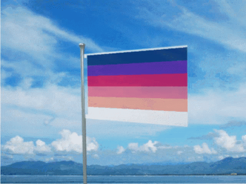 A Flag With A Rainbow Of Colors Is Flying In The Wind GIF