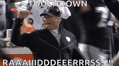 A Football Coach Is Raising His Fist In The Air While A Group Of Players Celebrate A Touchdown . GIF