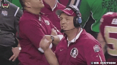 A Football Coach Wearing Headphones Is Giving A Thumbs Up To His Team GIF