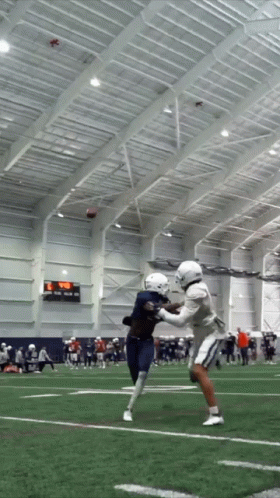 A Football Game Is Being Played In An Indoor Stadium With A Scoreboard Showing A Score Of 29 To 0 GIF