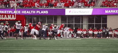 A Football Game Is Being Played In Front Of A Banner That Says Caresource GIF