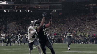 A Football Game Is Being Played In Front Of A Sign That Says Home Of The 12S GIF