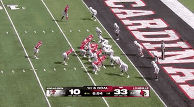 A Football Game Is Being Played On A Field With A Banner That Says Cardinals On It . GIF