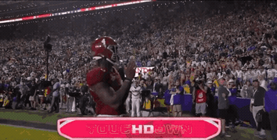 A Football Player Celebrates A Touchdown In Front Of A Large Crowd GIF