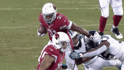 A Football Player For The Cardinals Is Being Tackled By Another Player GIF