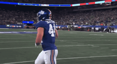 A Football Player For The New York Giants Is Walking On The Field GIF