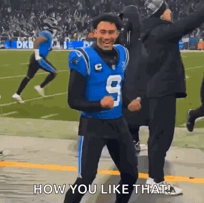 A Football Player In A Blue Jersey Is Dancing On The Field While A Crowd Watches . GIF