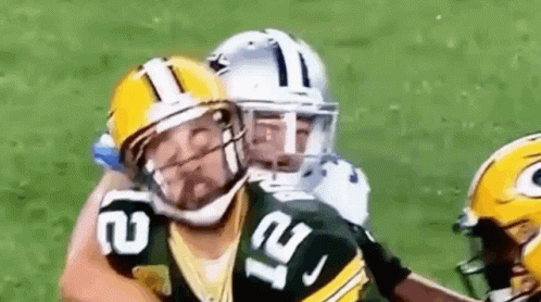 A Football Player In A Green Bay Packers Uniform Is Being Tackled By Another Player . GIF