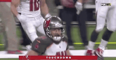 A Football Player In A Helmet Is Kneeling On The Field . GIF