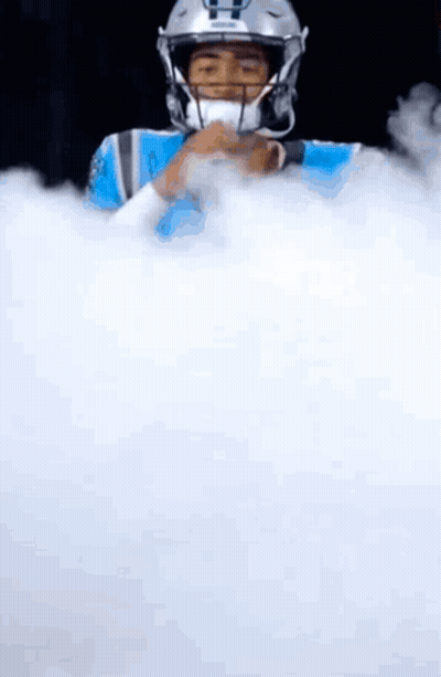 A Football Player In A Helmet Is Surrounded By White Smoke . GIF