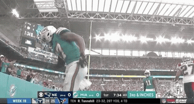 A Football Player In A Miami Dolphins Uniform Is Running Towards The Goal GIF