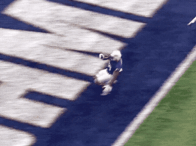 A Football Player In A Purple Jersey Is Being Tackled GIF