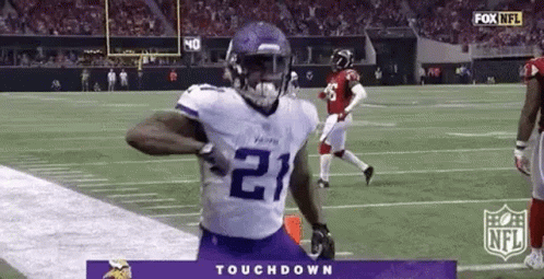 A Football Player In A Purple Jersey Is Running Down The Field . GIF