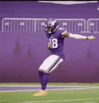 a football player in a purple uniform is jumping in the air on the field .