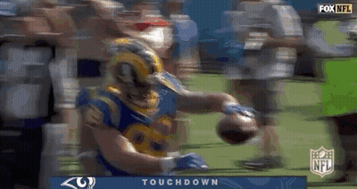 A Football Player In A Rams Jersey Is Holding A Football In His Hands . GIF