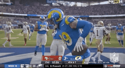 A Football Player In A Rams Uniform Is Running With The Ball During A Game . GIF
