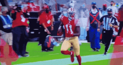 A Football Player In A Red And Gold Uniform Is Running With The Ball On A Field . GIF
