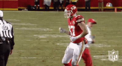 A Football Player In A Red And White Uniform Is Running On A Field . GIF