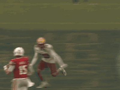 A Football Player In A Red Jersey And White Pants Is Being Tackled By Another Player On The Field . GIF