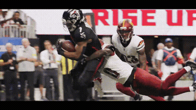 A Football Player In A Red Uniform Is Being Tackled By Another Player In A Black Uniform GIF