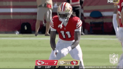 A Football Player In A Red Uniform Is Standing On The Field . GIF