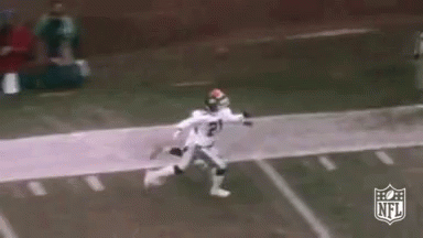 A Football Player In A White Uniform Is Running Down The Field . GIF