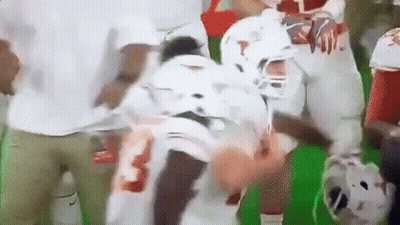 A Football Player Is Being Helped Off The Field By A Group Of People . GIF