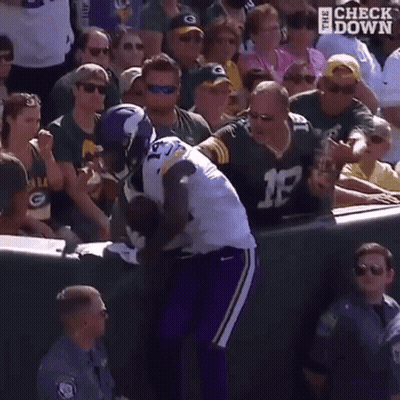 A Football Player Is Being Tackled By A Fan While A Crowd Watches . GIF