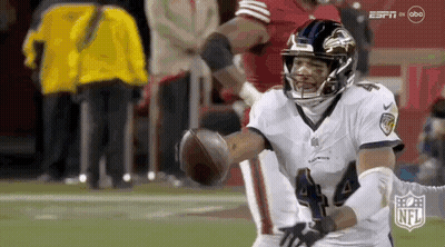 A Football Player Is Catching A Ball On A Field During A Game . GIF
