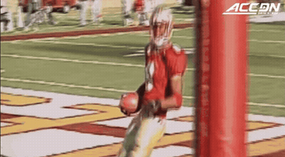 A Football Player Is Holding A Ball In Front Of A Red Pole That Says Accon On It GIF