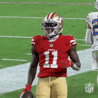 A Football Player Is Holding A Ball On The Field . GIF