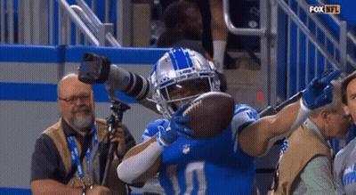 A Football Player Is Holding A Football In His Hands While A Cameraman Takes A Picture Of Him GIF