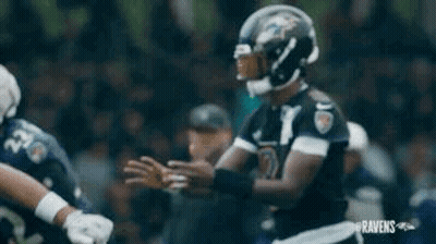 a football player is holding a football in his hands while standing on a field .