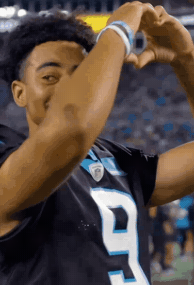 A Football Player Is Making A Heart Shape With His Hands During A Game . GIF