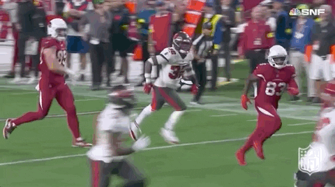 A Football Player Is Running On A Field During A Game . GIF