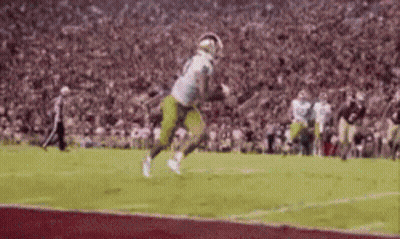 A Football Player Is Running On A Field With A Ball In His Hand . GIF