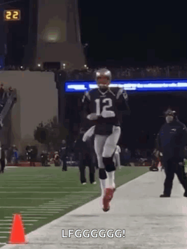 A Football Player Is Running On A Field With A Cone In The Foreground . GIF