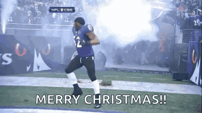 A Football Player Is Running On A Field With Smoke Coming Out Of The Stands And The Words `` Merry Christmas ! '' GIF