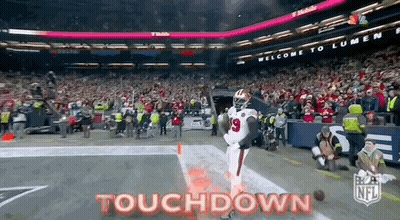 A Football Player Is Running On The Field With The Words Touchdown Written On The Bottom . GIF