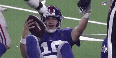 A Football Player Is Sitting On The Ground Holding A Football In His Hand . GIF