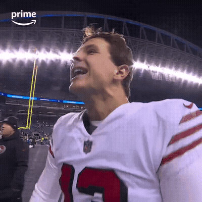 A Football Player Is Smiling In Front Of A Stadium That Says Prime On The Bottom GIF