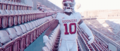 A Football Player Is Standing In A Stadium With Empty Seats . GIF